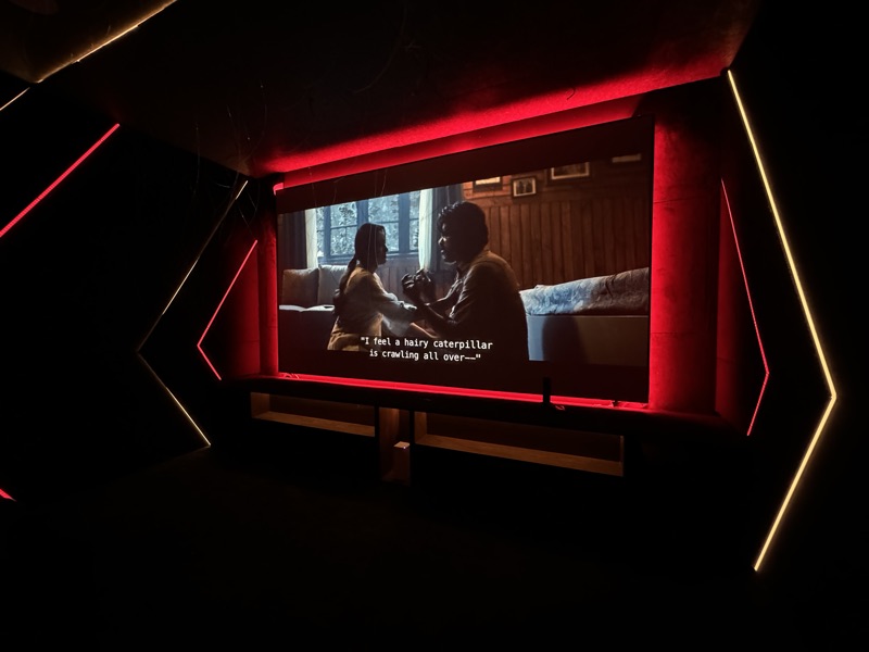 A private cinema screen framed by red accent lighting and geometric illuminated wall details.
