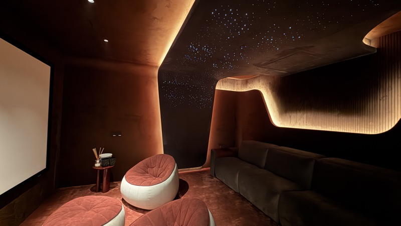 A private screening space with curved detailing, a projection screen and lounge seating.