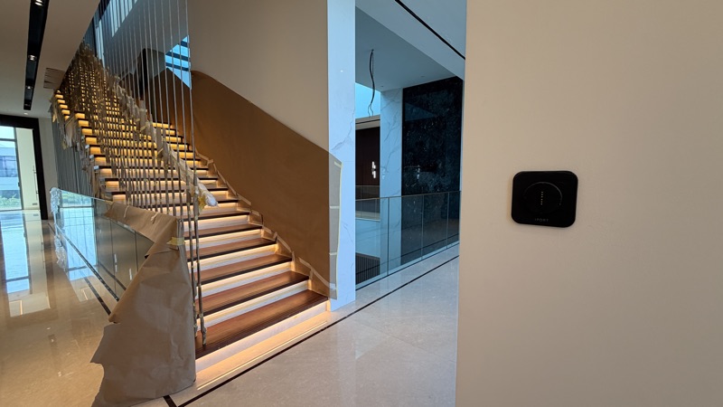 Illuminated staircase with a wall-mounted control dock, photographed during installation.
