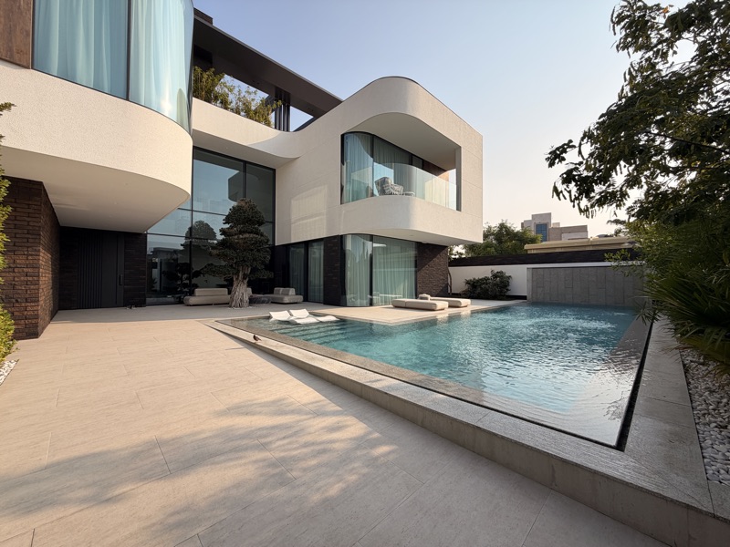 A contemporary villa with curved glazing, pool and outdoor seating.