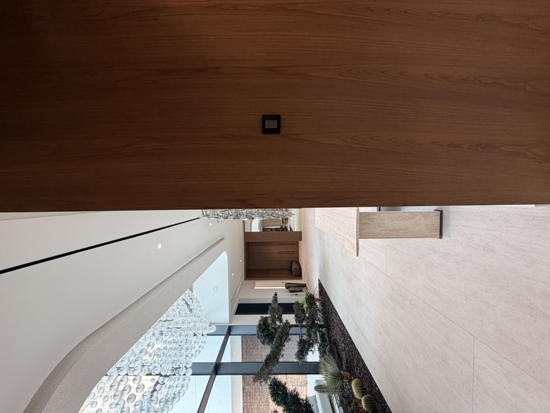 A compact wall keypad set into timber panelling beside an open living space.